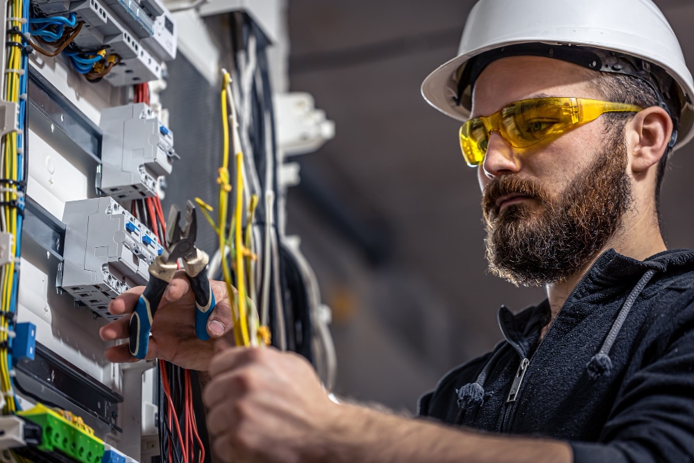 male-electrician-works-switchboard-with-electrical-connecting-cable