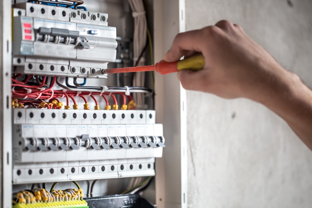 man-electrical-technician-working-switchboard-with-fuses-installation-connection-electrical-equipment-close-up